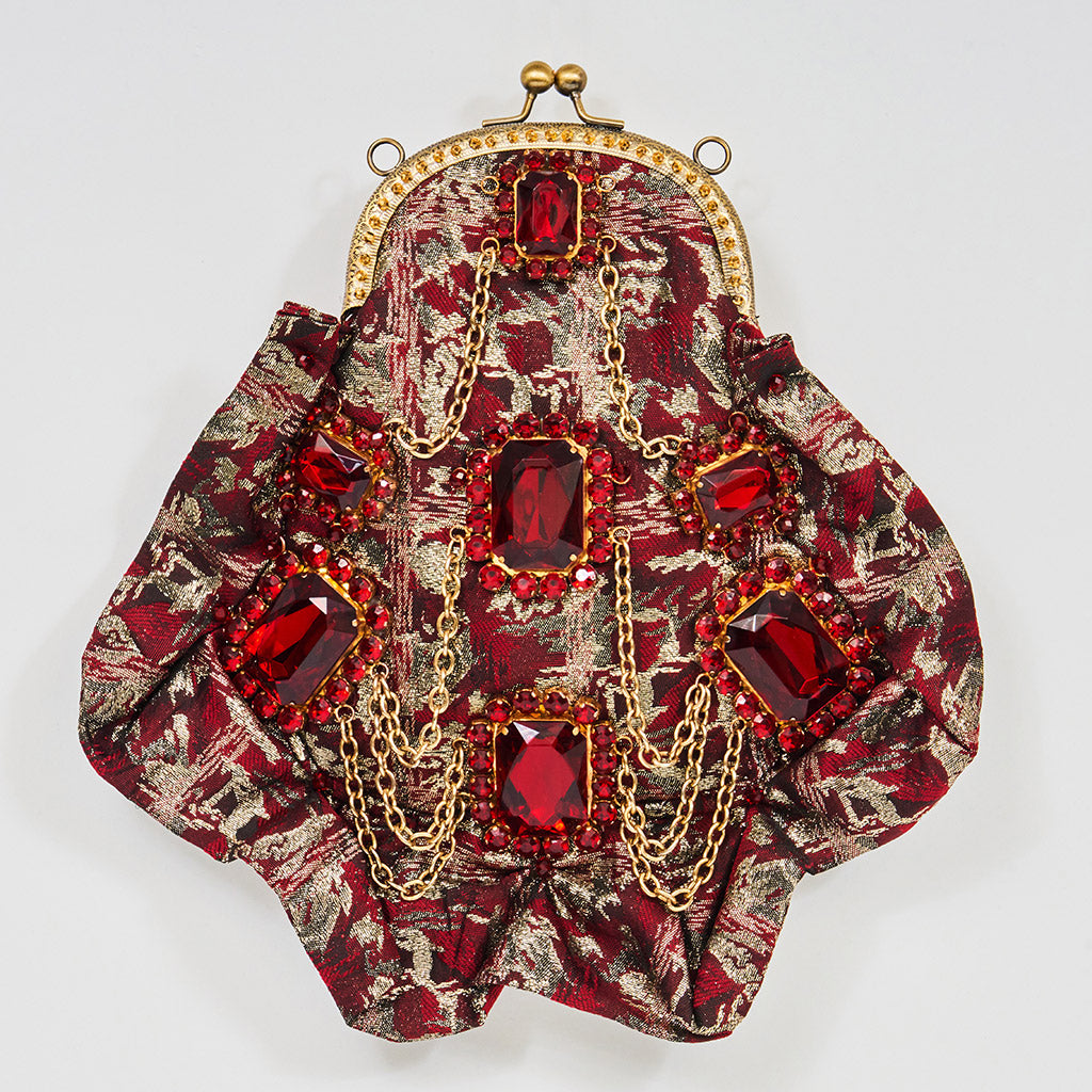 Meet Gapsy. A burgundy, gold & red shimmer handbag, adorned with super size red rhinestones and gold chain features.