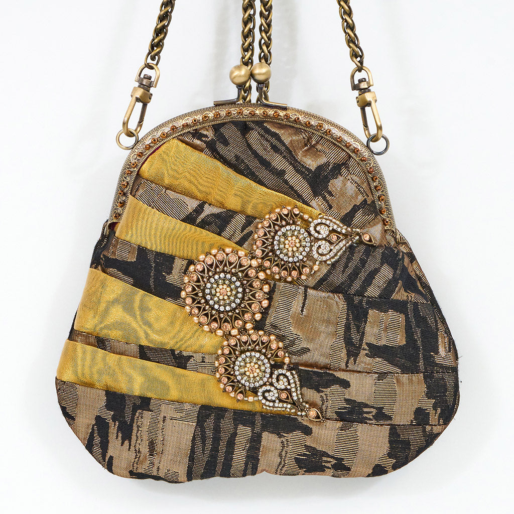 Meet Olympia. A gold, brown and black handbag with circular pearl motifs.