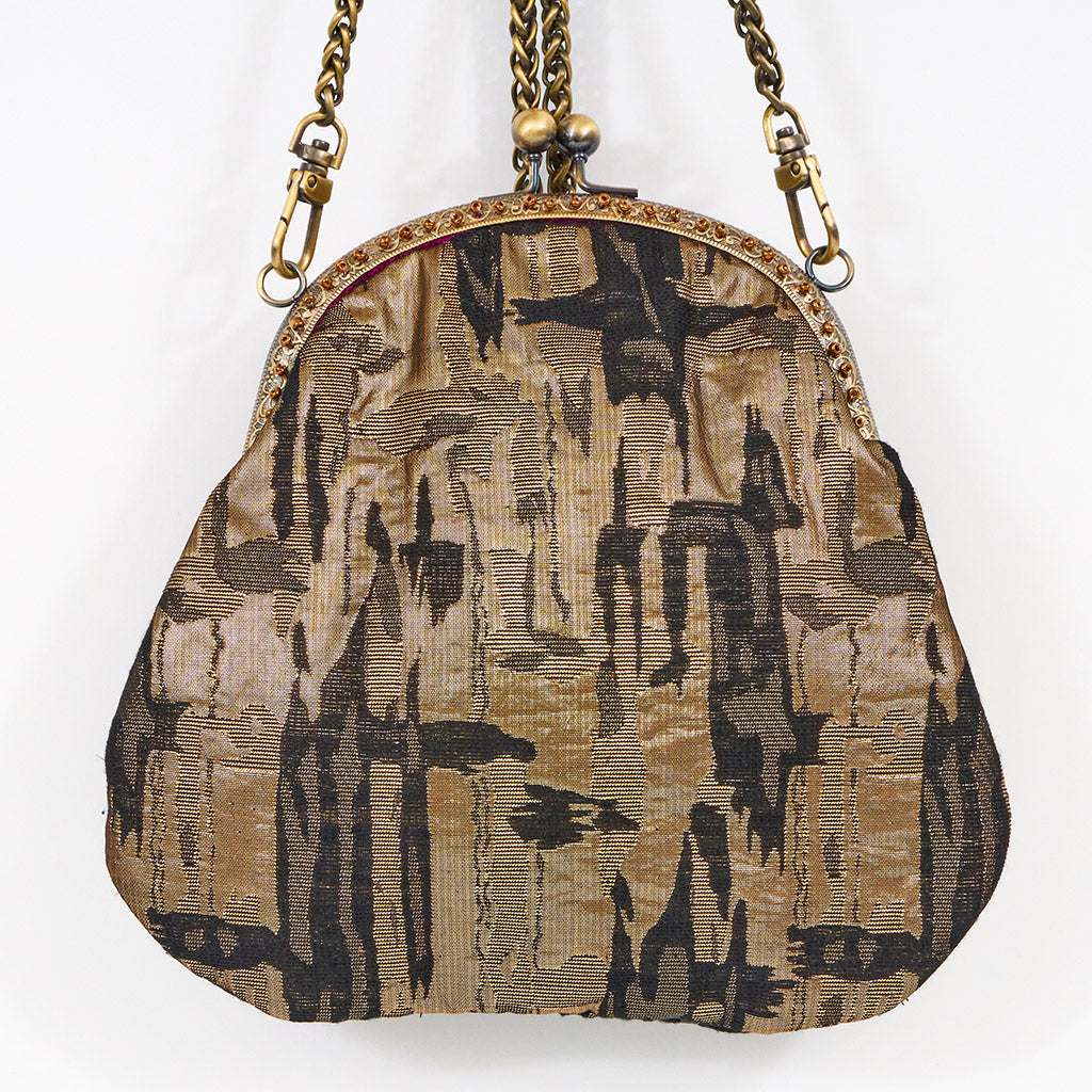 Meet Olympia. A gold, brown and black handbag with circular pearl motifs.