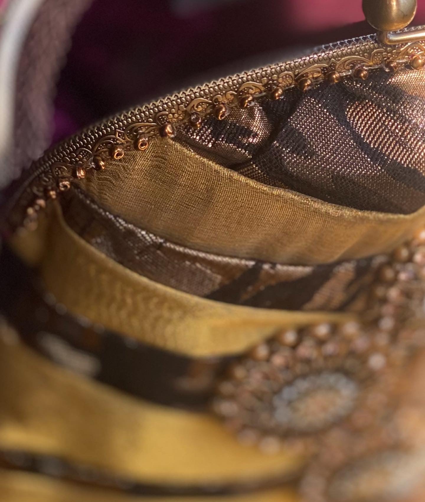 Meet Olympia. A gold, brown and black handbag with circular pearl motifs.
