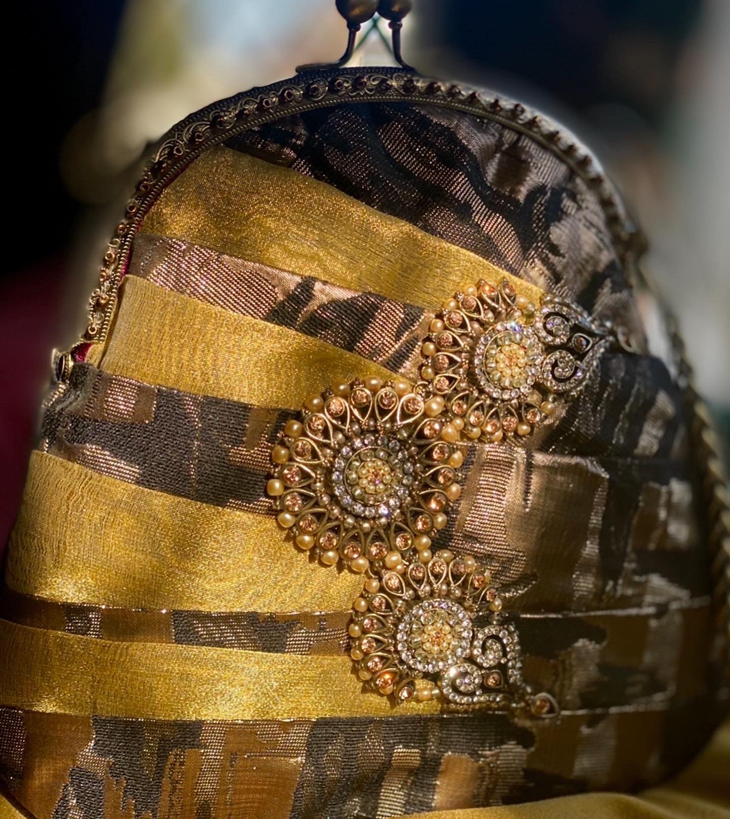 Meet Olympia. A gold, brown and black handbag with circular pearl motifs.
