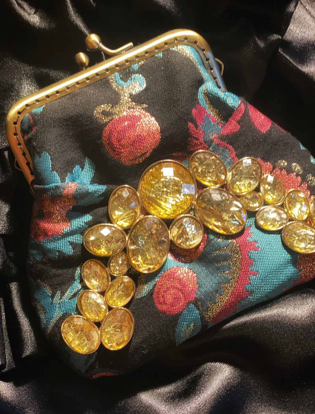 Meet Brigitte. A wristlet purse of black, blue and pink flowers, with a garland of gold rhinestones.