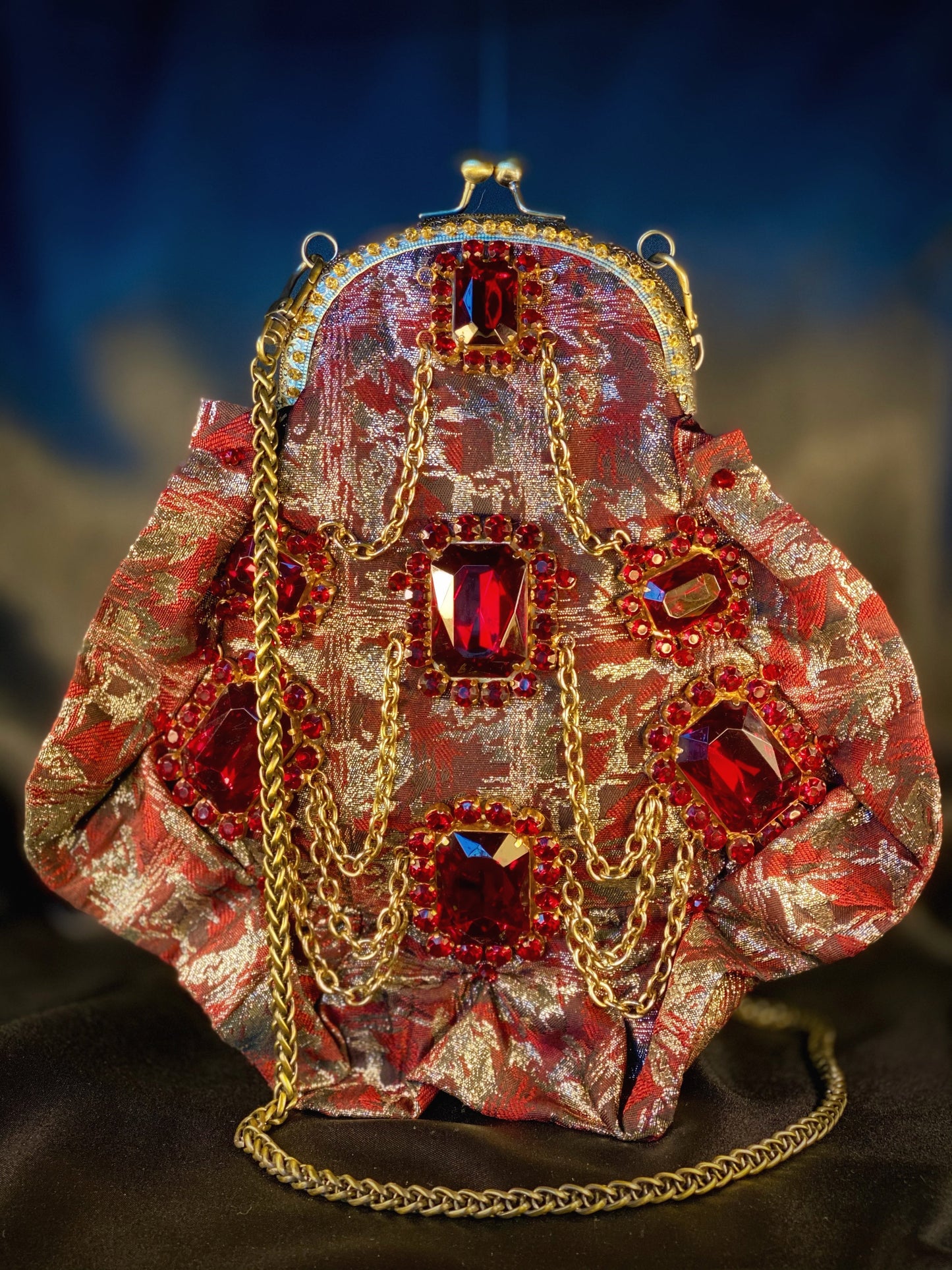 Meet Gapsy. A burgundy, gold & red shimmer handbag, adorned with super size red rhinestones and gold chain features.
