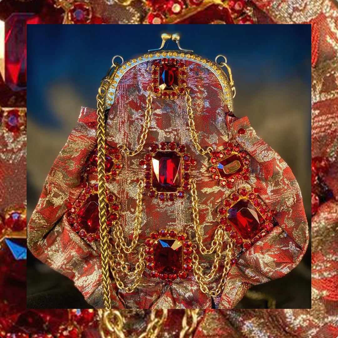 Meet Gapsy. A burgundy, gold & red shimmer handbag, adorned with super size red rhinestones and gold chain features.