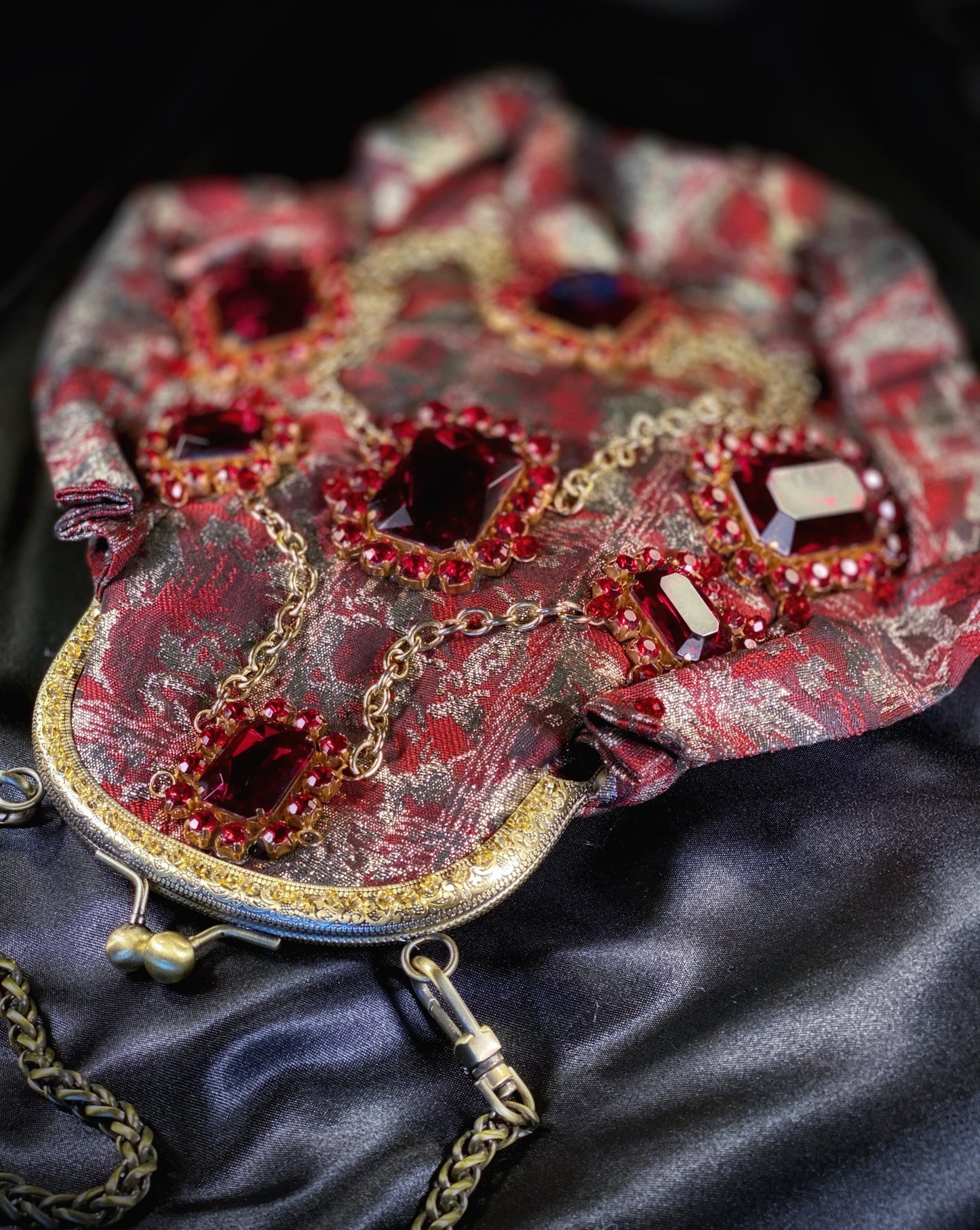 Meet Gapsy. A burgundy, gold & red shimmer handbag, adorned with super size red rhinestones and gold chain features.