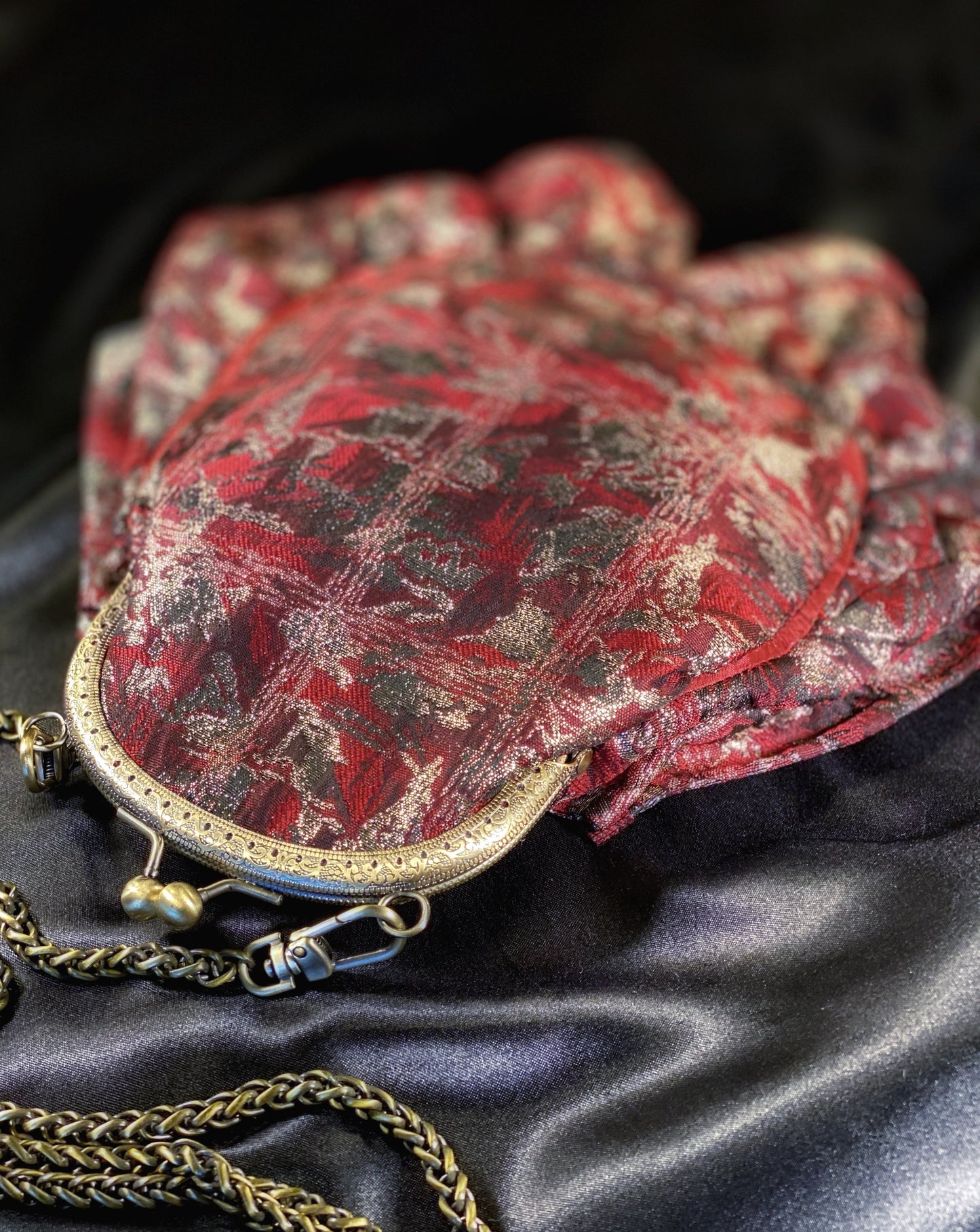 Meet Gapsy. A burgundy, gold & red shimmer handbag, adorned with super size red rhinestones and gold chain features.